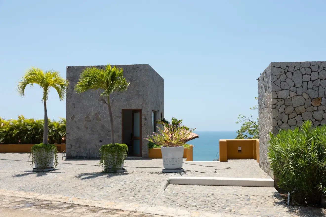 Acceso empedrado a la villa con palmeras y el mar de fondo