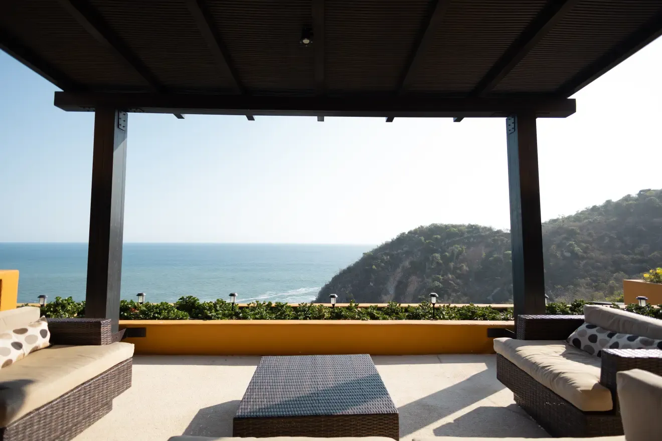 Sala exterior bajo la pérgola con vista al océano y a los riscos
